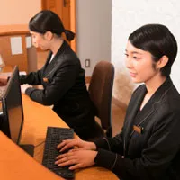 レセプション担当がPCを操作しているイメージ画像