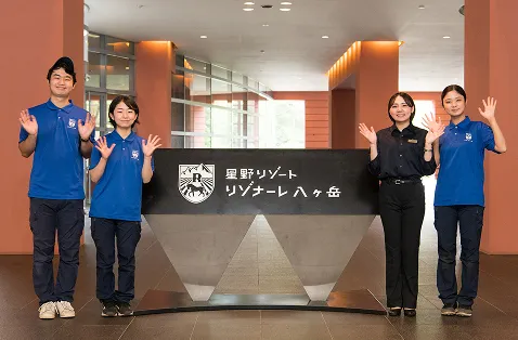 インターンに参加した生徒達とエントランスのラグジュアリーなホテルサイン（名称看板、銘板）