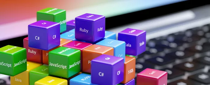 PCの手前に積み上げられた、プログラミング言語が書かれたキューブにピントが合っている画像