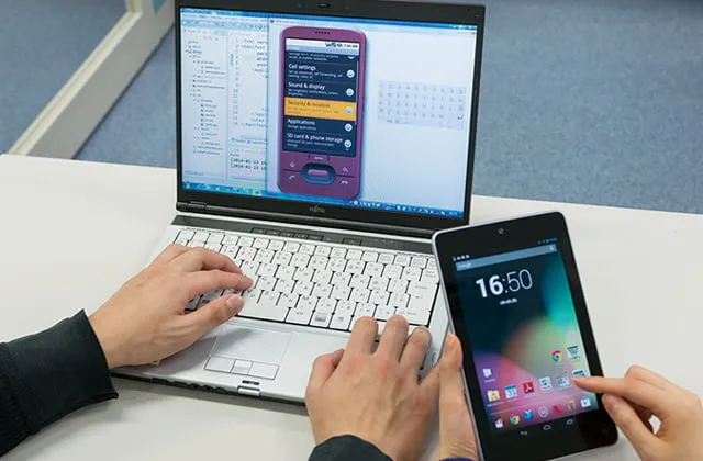 開発したシステムの使用感をスマホで確認している手元