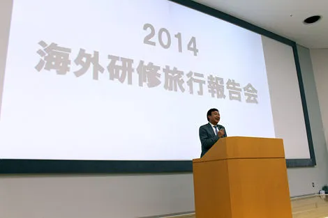 壇上で海外研修旅行報告会の挨拶をする理事長