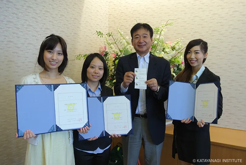 留学生3名が任命証を持ち、理事長が親善大使の名刺を持って記念撮影