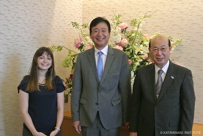 清楚なアレンジメントフラワーをバックに、国際交流員、理事長、大田区長で記念撮影