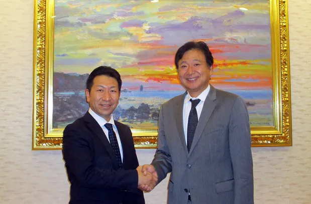 絵画の前で社長と握手をして記念撮影