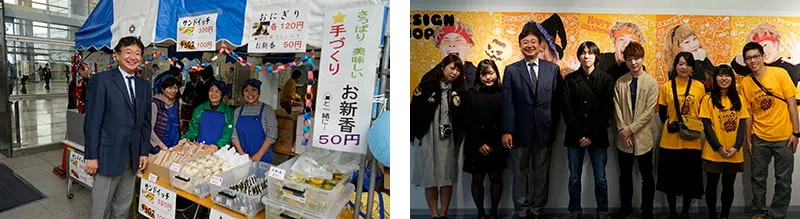 左にサンドイッチ、おにぎり、お新香などを売っている地元商店街振興組合さまのテントと、右に学生作品展の華やかな展示の前で学生スタッフたちとの記念写真