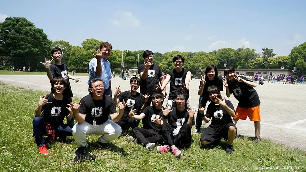 黒のTシャツの学生達と、流行のポーズらしい親指、人差し指、小指を立てたポーズで記念撮影