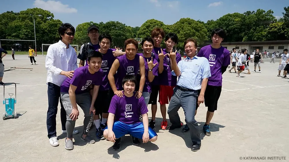 紫のTシャツを着た学生達とお揃いのポーズで記念撮影