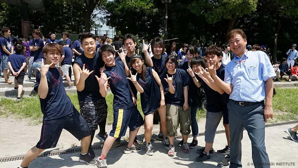 濃紺にピンクのプリントが入ったTシャツの学生たちと、流行中のポーズと少し反ったお揃いの体勢で1枚