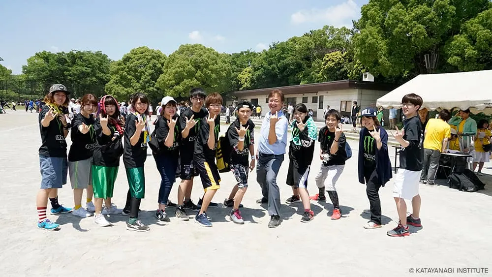 大流行中のポーズを黒いTシャツの学生たちと、一歩足を踏み出したポーズで記念撮影