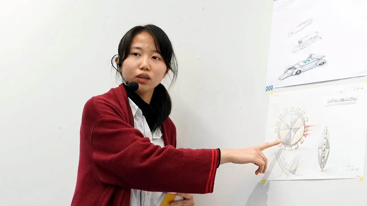 制作したサムネイルを壁に貼り、指差しながら聴衆も見て話している様子