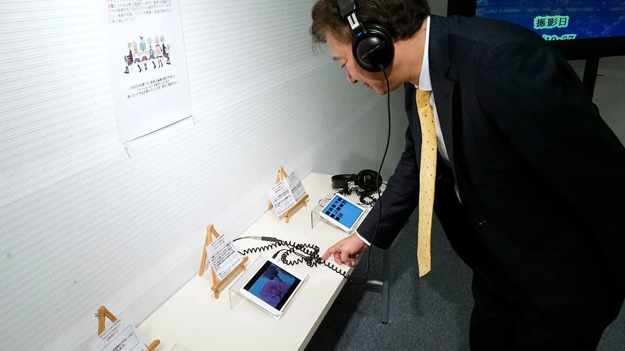 小さなモニターに接続されたヘッドフォンを装着し、耳からも楽しんでいる校長の写真