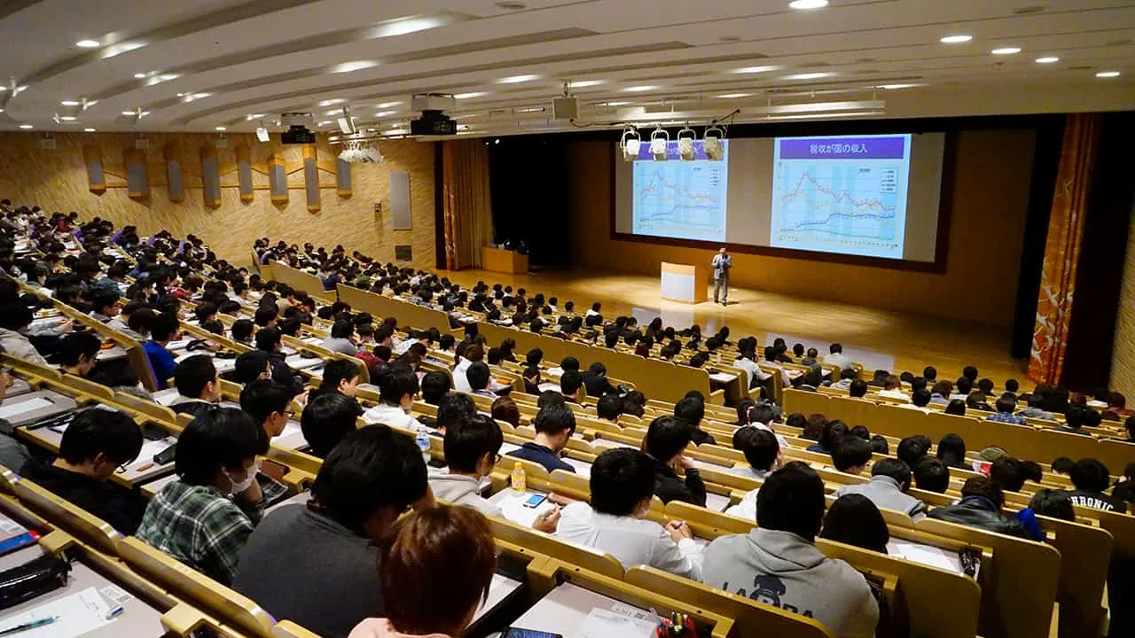 講義中の壇上を階段状の座席の後方から、斜めの角度で撮影した写真