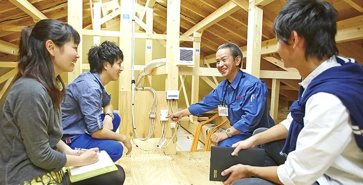 屋根裏に上がり実際の設備を見ながら説明を受けている様子