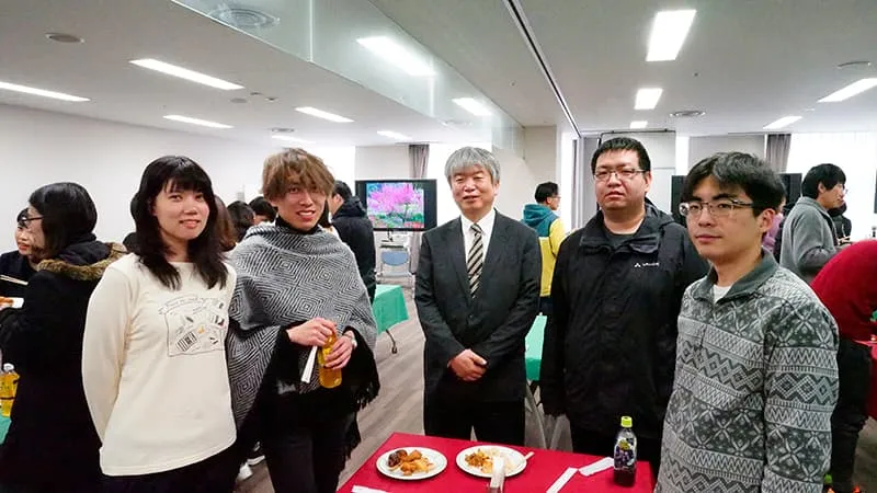 立食式の会場で、料理をテーブルに置き講師と談笑していたグループを撮影した写真