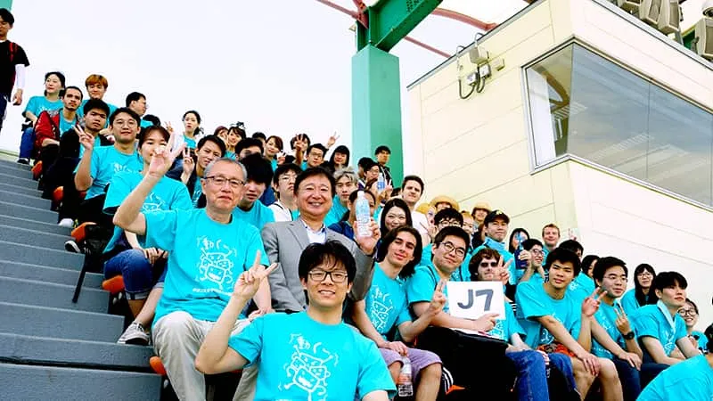 水色のお揃いTシャツを着た留学生のみなさんと千葉理事長