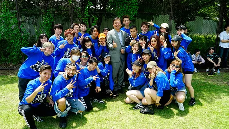 青いお揃いロンTを着たダンスパフォーマンス科学生のみなさんと千葉理事長