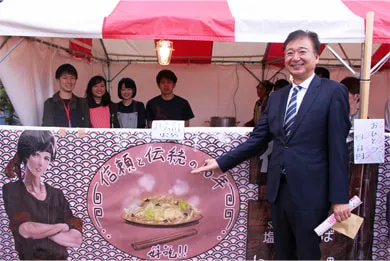 店舗前でマンガ・アニメーション科の皆さんと記念撮影する千葉理事長