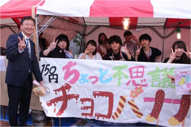 店舗前で放送芸術科の皆さんとピースサインで記念撮影する千葉理事長