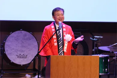 赤い法被を着て挨拶をする千葉理事長