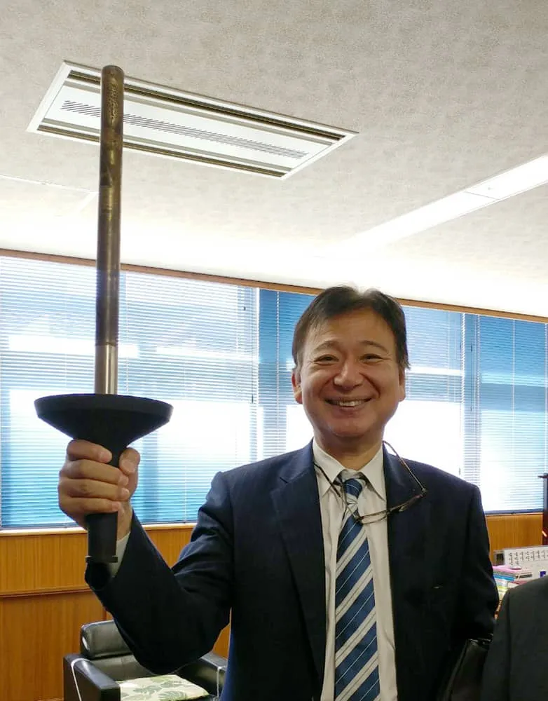 右手でトーチを掲げ嬉しそうに笑う千葉理事長