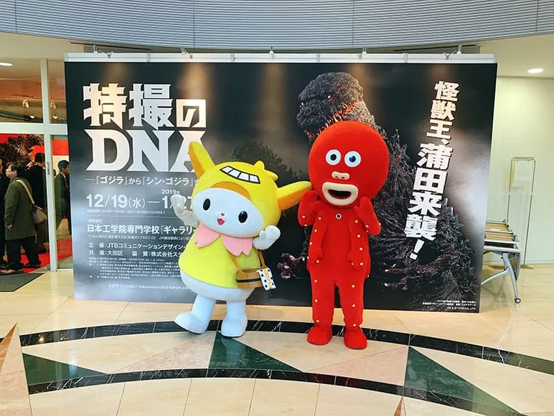 特撮のDNA特大ポスターの前で記念撮影している2人のゆるキャラ