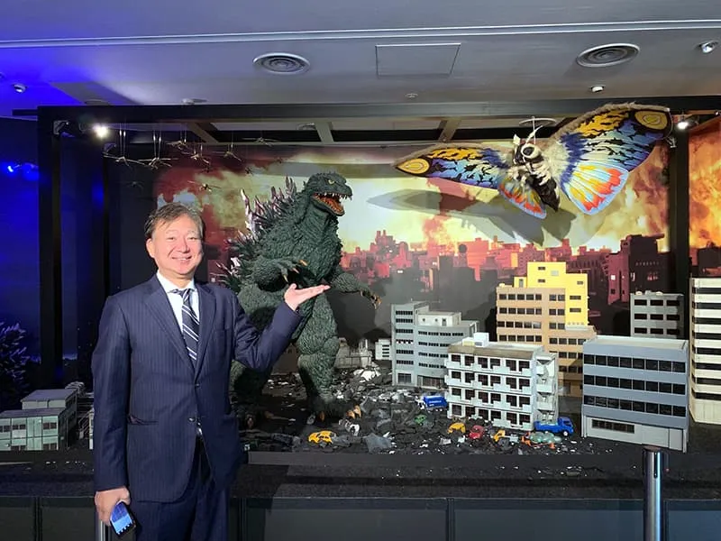 ゴジラVSモスラの撮影ミニチュアをバックに記念撮影をする千葉理事長