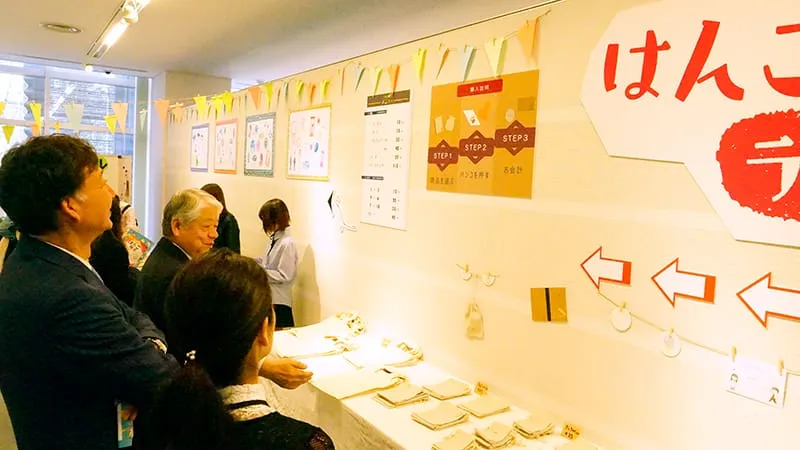はんこラボの展示物を見上げ楽しそうに笑う千葉理事長