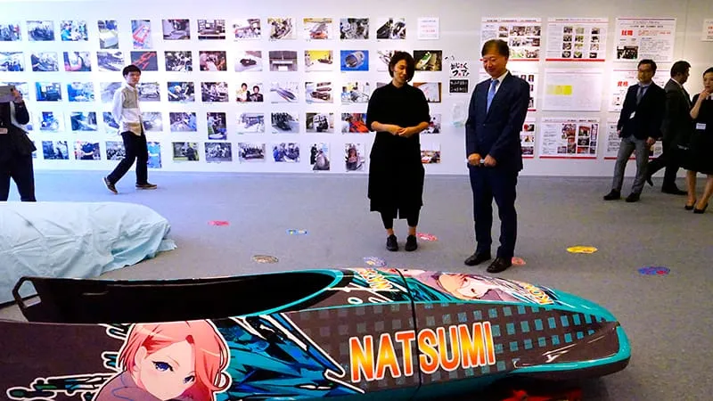 下町ボブスレー展示を見ながら会話をする千葉理事長とオリンピック選手 浅津このみさん