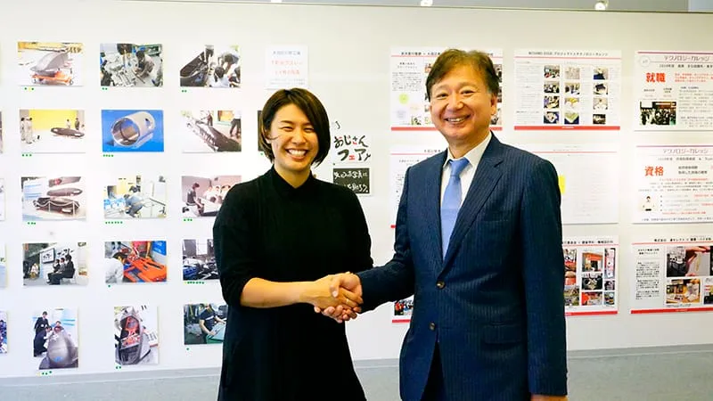 展示物の前で固い握手を交わす千葉理事長と浅津さん