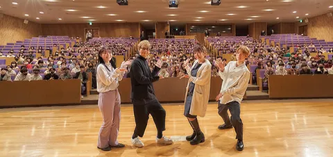 壇上から沢山の学生をバックに撮影する山寺さんと富永先生と学生2人