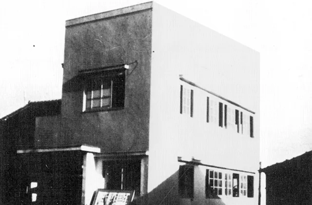 コンクリート製に見える簡素な建物の白黒写真