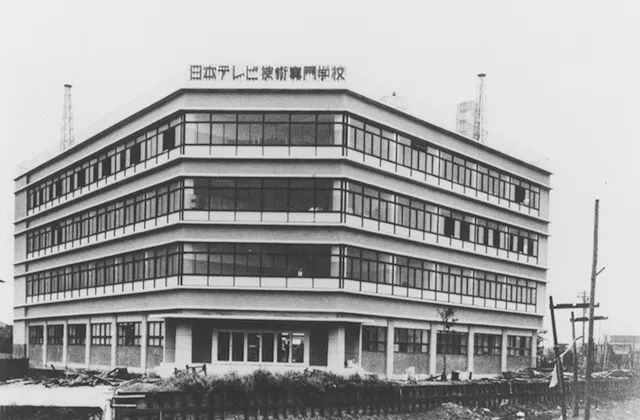 4階建ての壁面がほぼガラス張りと言える、凝った外観をした建物の白黒写真