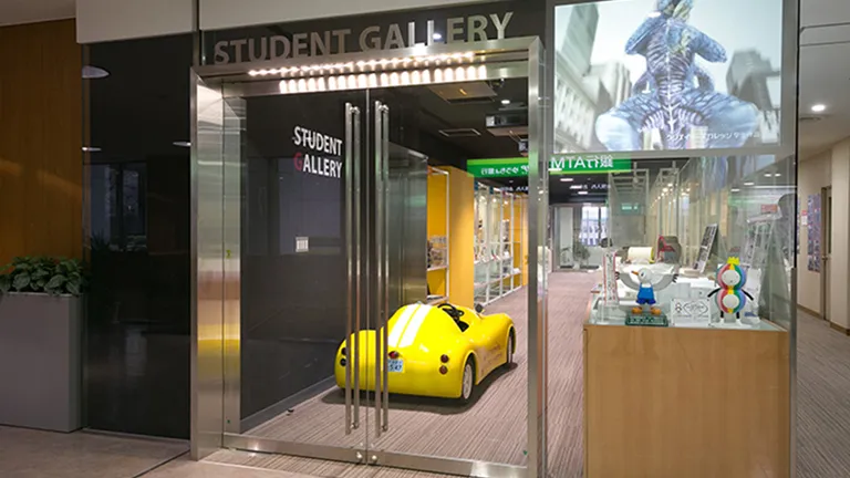 小さな小さな1人乗りの黄色いオープンカーがガラスドアの向こうに見える高級感がある入口の様子