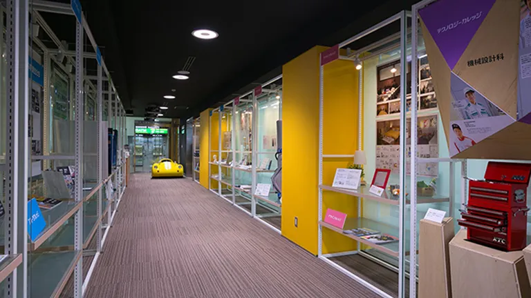 長い絨毯敷きの廊下と左右の棚状になった壁に生徒の力作が展示されたアートな空間