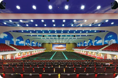 手前と左右に階段状の観客席があり、シートを敷いたアリーナの床にたくさんのパイプ椅子が並べられ、ステージには赤富士の緞帳が引かれた公演仕様の画像