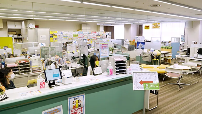 オープン型のオフィスに受付カウンターと相談用のデスクコーナーが配置されている風景