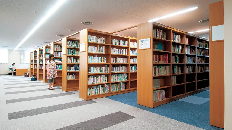 大容量の背が高い本棚が余裕のある間隔で並んでいるゆとりある図書館の風景
