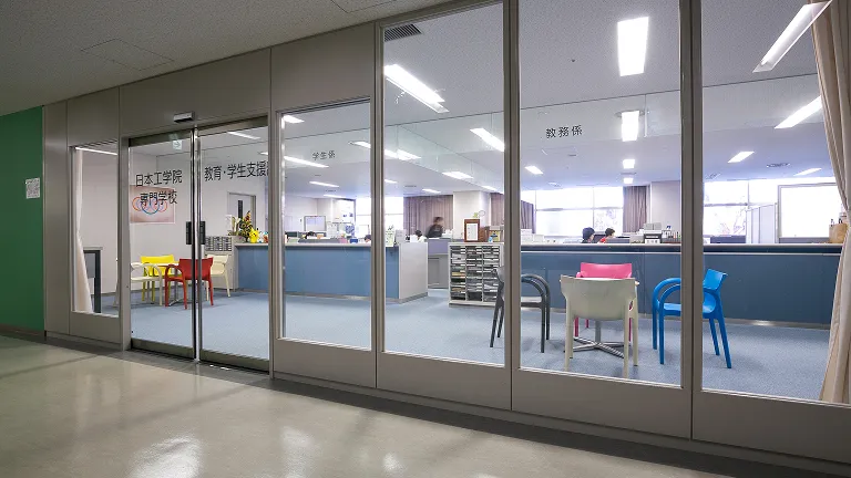 ガラス張りの壁の入り口からカウンター越しのオープン型オフィスを撮影した画像