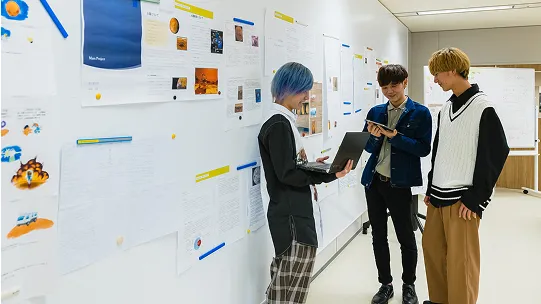 学生たちがパソコンやタブレットを見ながら話し合っている様子