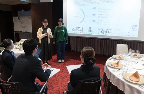 学生がスクリーンを使ってプレゼンテーションを行う様子