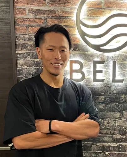 笑顔で正面を向き腕を組んでいる塩原 航さん