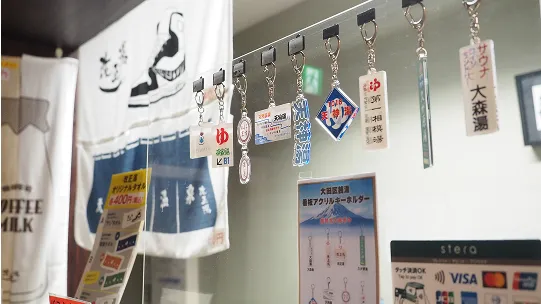 カウンターに並んだ温泉施設のキーホルダーや暖簾