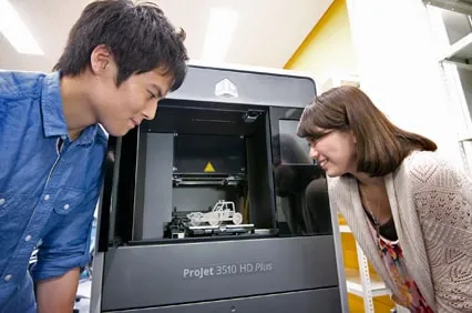 3Dプリンターのコンテナの中にある製作物をのぞき込んでいる生徒の様子