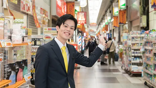 学生が笑顔で商店街をガイドする様子