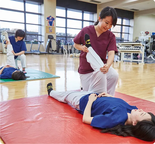 下肢のストレッチ技術を練習する学生