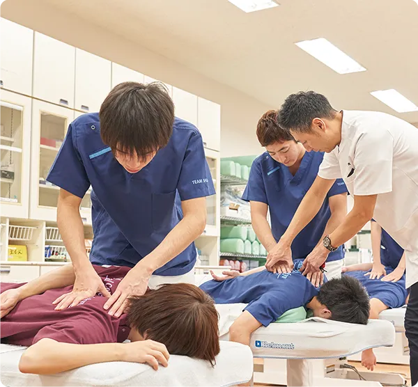 背部の手技療法を練習する学生たち