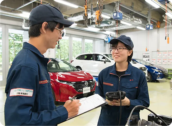 自動車整備実習で点検内容を確認する学生