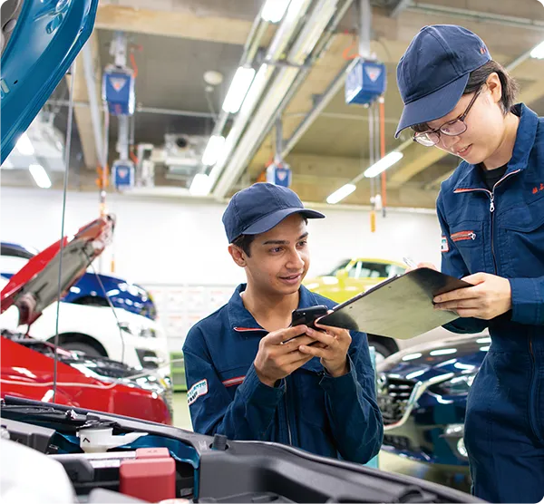 自動車整備実習の点検内容をタブレットで確認する学生