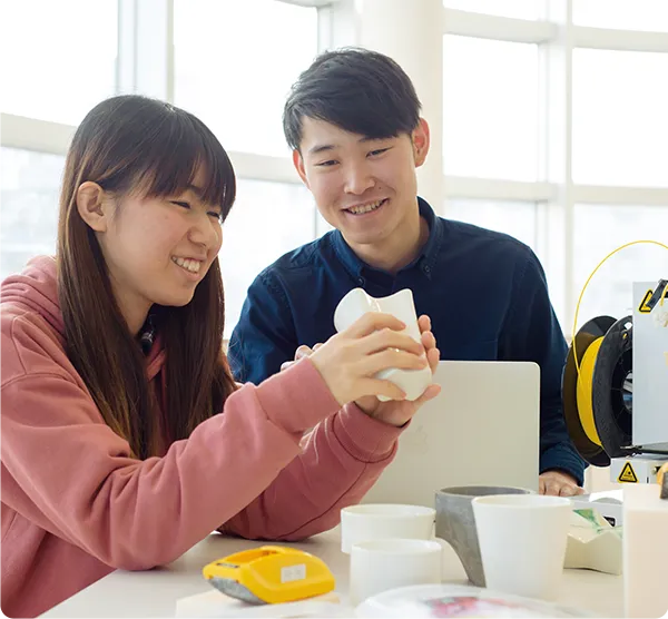 ２名の学生が卓上の雑貨を手に取って確認している様子