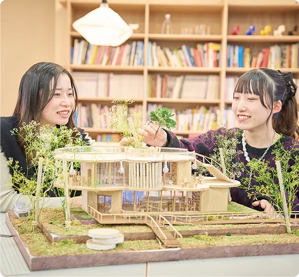 ２名の学生が建築模型に木々を添えている様子
